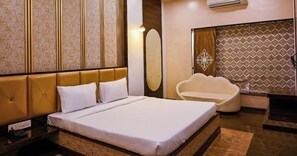 Camera d'albergo con un letto grande, un'area salotto, un condizionatore d'aria a parete e una parete decorata con motivi.
