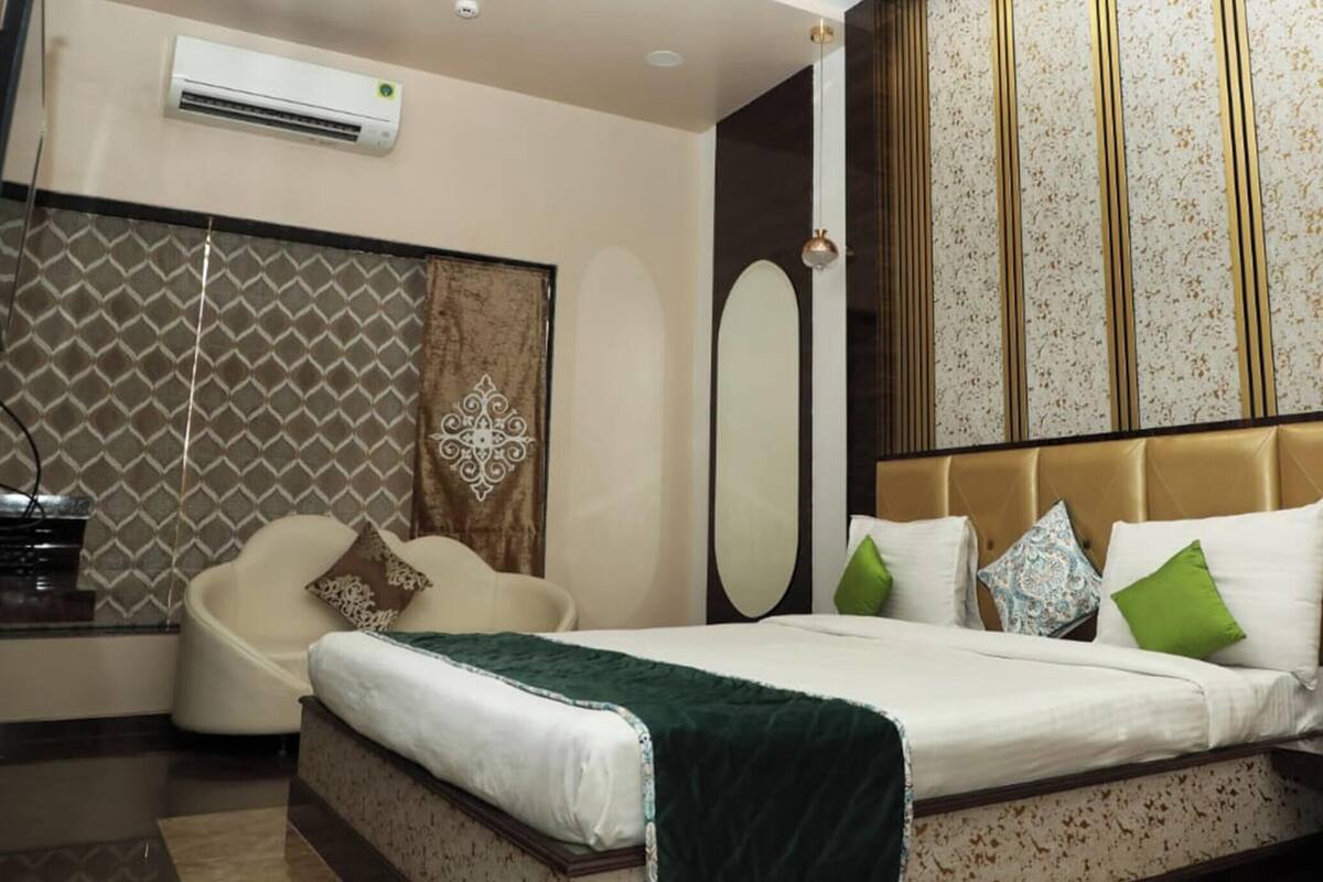 A hotel room with a bed, bedside table, chair, and a large mirror.