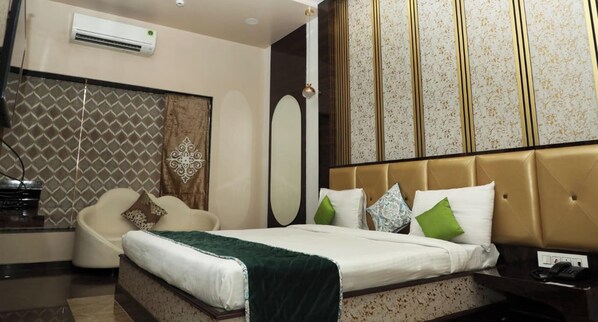 Una habitación de hotel con cama, mesita de noche, silla y un espejo grande.
