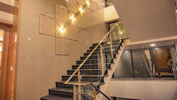 Una moderna scala con ringhiere in vetro, un design geometrico della parete e una persona che scatta una foto.