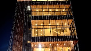 Un hotel con un cartello ben visibile, un gruppo di persone davanti e una moquette rossa.