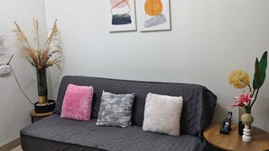 Una sala moderna con un sofá gris, una mesita redonda y dos obras de arte colgadas en la pared.
