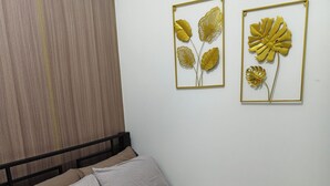 Una cama bien hecha con ropa de cama a rayas, una toalla enrollada y dos cuadros enmarcados.