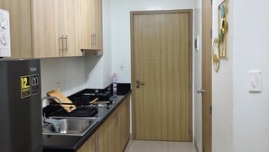 Una cocina con armarios de madera, un refrigerador negro, un fregadero y una puerta que da a otra habitación.