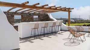 Un bar en la azotea con paredes de piedra, pérgola de madera y asientos al aire libre.