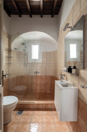Ein Badezimmer mit Dusche, Toilette, Waschbecken und Spiegel.