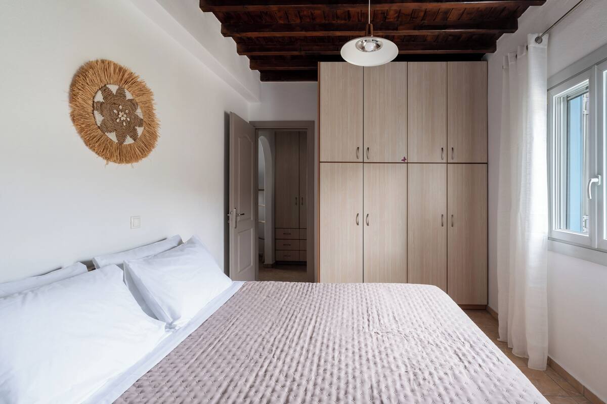 Quarto com cama, guarda-roupa e luminária pendente.