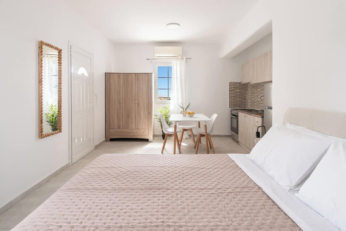 Quarto com cama, escrivaninha e cozinha compacta.