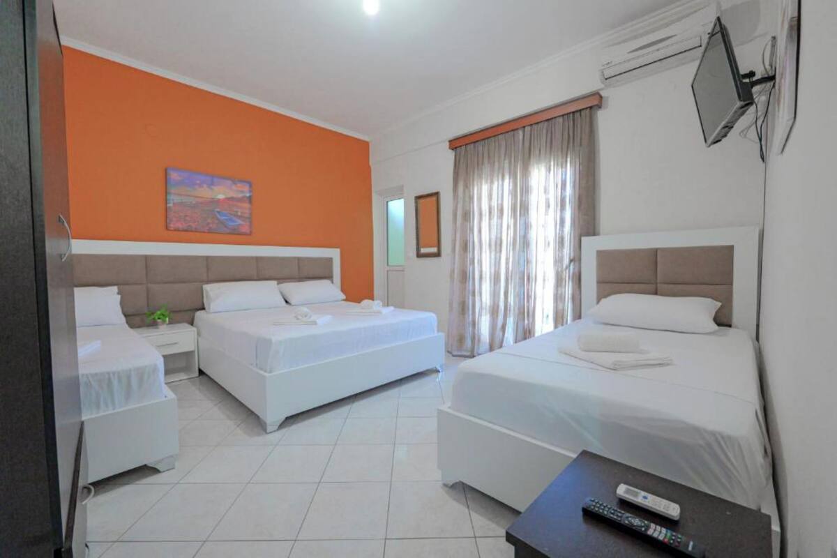A hotel room with two beds, a television, and a painting on the wall.