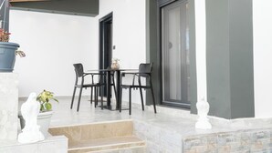 A patio with a table and chairs, a potted plant, and a white statue. - Villa Rafail (Ksamil)