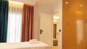 A hotel room with a bed, a wardrobe, and a door leading to another room. - Villa Rafail (Ksamil)