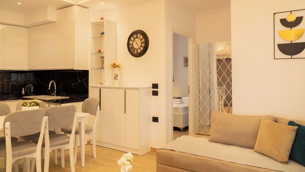 A modern living room with a sofa, chairs, a dining area with a table, and a kitchen with a black countertop. - Villa Rafail (Ksamil)