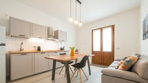 A modern kitchen with white cabinets, a wooden dining table, and black chairs. - 'Luxi Teulada' Apartment with Wi-Fi and Air Conditioning (Teulada)