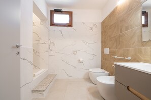 A bathroom with a bathtub, toilet, and vanity. - The Essence of Light in a Designer Apartment in Teulada (Teulada)