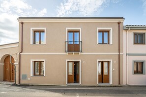 A two-story building with a balcony, a wooden door, and a window. - The Essence of Light in a Designer Apartment in Teulada (Teulada)