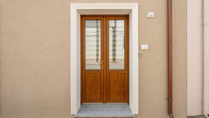 Pared beige con una puerta doble de madera, un letrero con el número '34' y una tubería marrón.