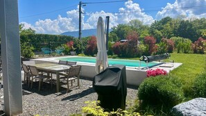 Un patio con piscina, mobiliario exterior y zona de barbacoa.
