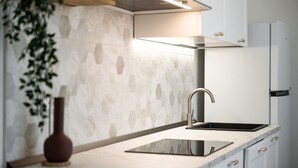 Cozinha moderna com bancada de mármore, torneira de aço inoxidável e forno embutido.