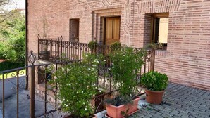 A brick building with a balcony, potted plants, and a metal railing. - El Patio de la Morera I and II (El Rasillo de Cameros)