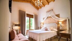 A bedroom with a bed, a desk, a chair, a chandelier, and a window with curtains. - El Patio de la Morera I and II (El Rasillo de Cameros)