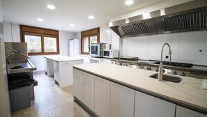 A modern kitchen with a central island, built-in microwave, and stainless steel range hood. - El Patio de la Morera I and II (El Rasillo de Cameros)