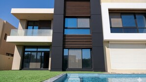 A modern two-story house with a swimming pool, large windows, and a garage. - 5 Rooms with private garden& Jacuzzi& Pool acc (New Administrative Capital)