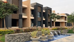 A modern building with a pool, surrounded by plants and a small waterfall feature. - 5 Rooms with private garden& Jacuzzi& Pool acc (New Administrative Capital)