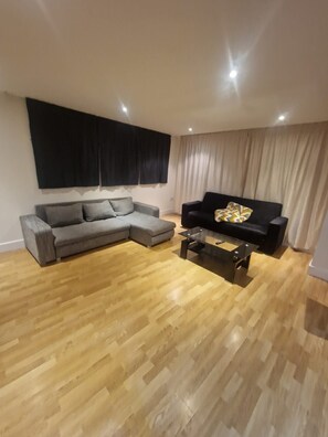 A living room with a grey sectional sofa, a black armchair, and a coffee table. - Central Luxurious Apartment London Bridge (London)