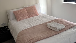 A neatly made bed with white and pink bedding, a folded towel, and a black bag on the floor. - Central Luxurious Apartment London Bridge (London)
