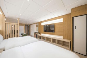 Camera d'albergo moderna con due letti, una panca in legno, una televisione e una porta.