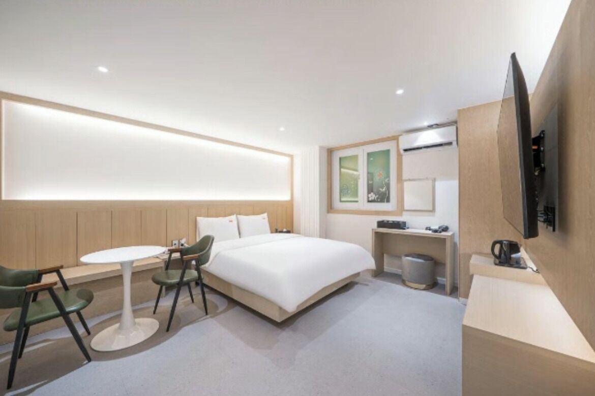 Een moderne hotelkamer met een bed, bureau, stoel, televisie en een klein tafeltje.