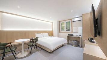 Een moderne hotelkamer met een bed, bureau, stoel, televisie en een klein tafeltje.