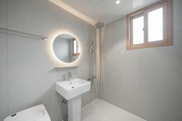 A modern bathroom with a pedestal sink, a shower, and a window. - DEUMEU HOTEL (Changwon)