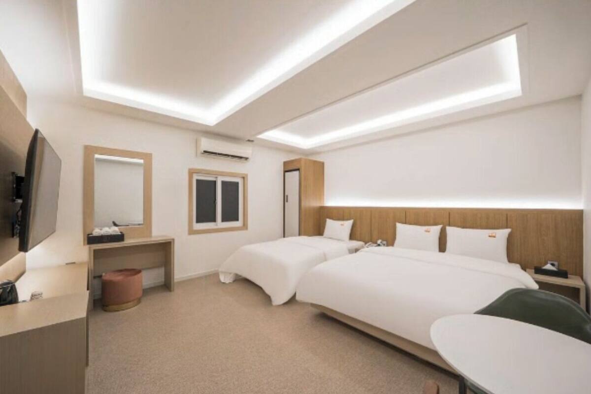 A hotel room with a large bed, a desk, a TV, and a ceiling light fixture.