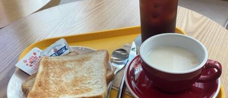 A tray with toast, a cup of soup, and a glass of iced tea on a table.