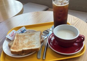 Una bandeja con tostadas, una taza de sopa y un vaso de té helado sobre una mesa.