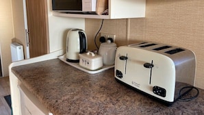 Una kitchenette equipada con microondas, tostadora, hervidor y un mueble pequeño.