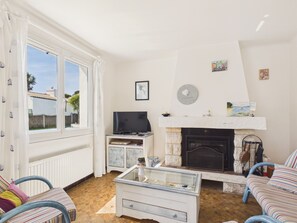 A living room with a fireplace, a television, and a window with curtains. - Holiday for 8 with pool, sea ​​300 m away (Barbâtre)