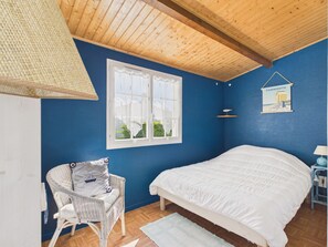 A bedroom with a bed, a wicker chair, a window, and a wall-mounted lamp. - Holiday for 8 with pool, sea ​​300 m away (Barbâtre)
