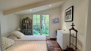 A bedroom with two beds, a bookshelf, a desk, and a window with a view of greenery. - Villa BOUGAINVILLEA, magnificent villa on the heights of Vence. (Vence)
