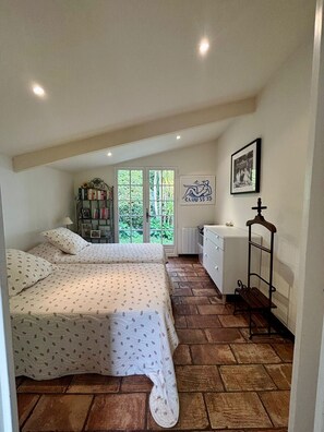 A bedroom with two beds, a bookshelf, a desk, and a window with a view of greenery. - Villa BOUGAINVILLEA, magnificent villa on the heights of Vence. (Vence)
