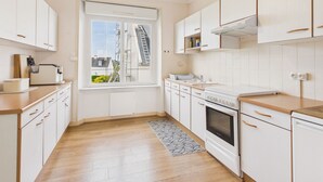 Eine Küche mit weißen Schränken, einem eingebauten Backofen, einem Fenster mit Blick nach draußen und einem Holzboden.