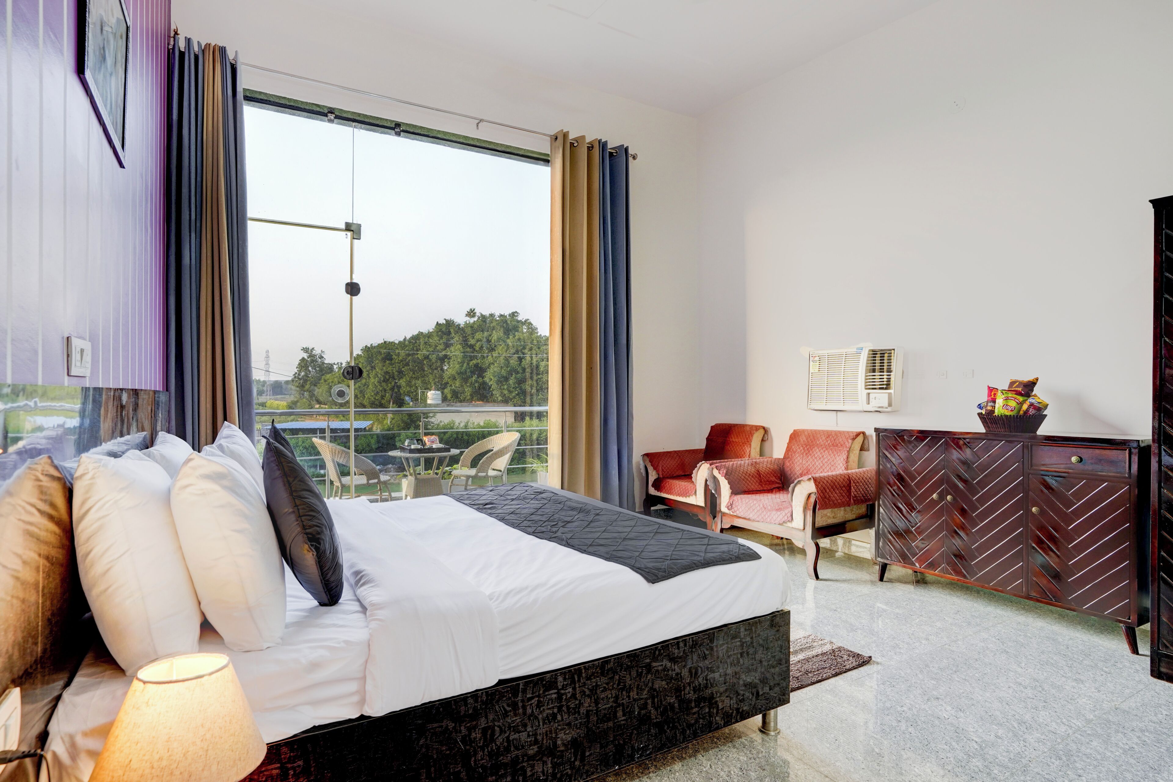 Habitación de hotel con cama, una silla, un armario y vistas al exterior.