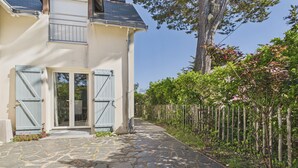 A house with a stone-paved entrance, a wooden fence, and a tree. - Family home: beach walk, garden & BBQ (Le Pouliguen)