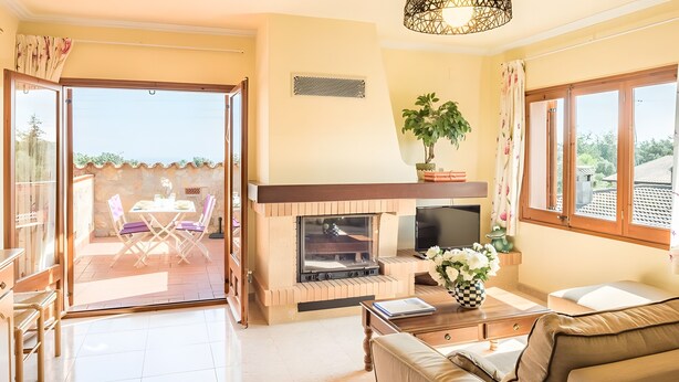 A living room with a fireplace, a sofa, a TV, and a dining area with chairs and a table. - Residencia occitania-building complex with 5 apartments (Calonge)