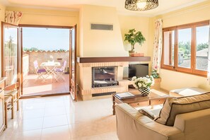 A living room with a fireplace, a sofa, a TV, and a dining area with chairs and a table. - Residencia occitania-building complex with 5 apartments (Calonge)