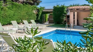 A swimming pool with lounge chairs, surrounded by greenery and a building with a tiled roof. - Residencia occitania-building complex with 5 apartments (Calonge)