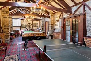 A billiards table, a pool table, and a dartboard in a room with stone walls and wooden beams. - Trimstone Manor - Paddock Cottage (Woolacombe)
