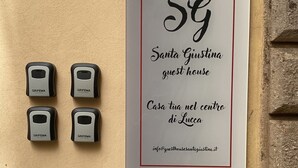 A sign for Santa Giustina guest house with four doorbell buttons labeled 'GRIFEMA' on a beige wall. - Guest Housa Santa Giustina (Lucca)