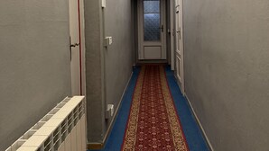 A hallway with a blue carpet, white walls, and a door at the end. - Guest Housa Santa Giustina (Lucca)